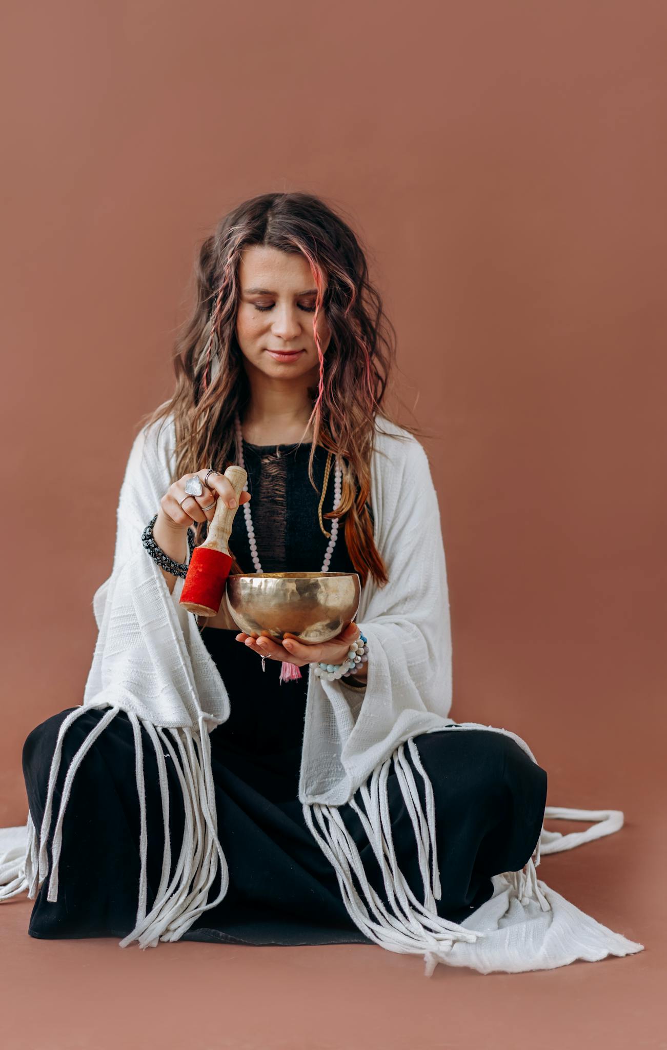 A serene woman meditates with a Tibetan singing bowl, promoting relaxation and mindfulness.