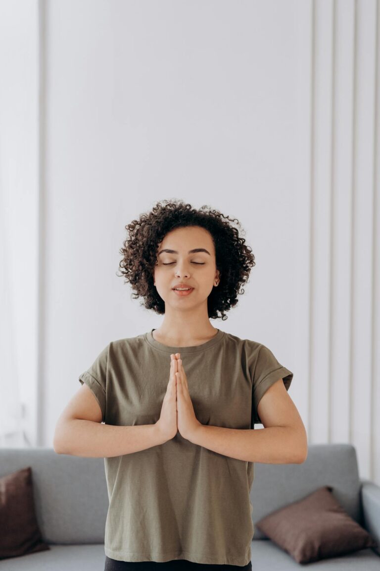 A woman meditating at home with closed eyes, enjoying tranquility and relaxation.